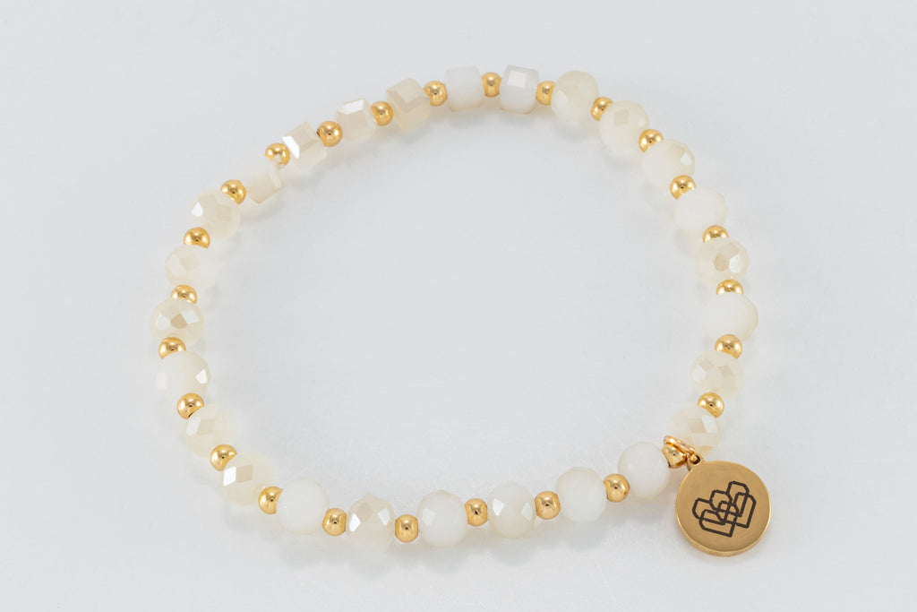 Bracelet is made with cream faceted beads and gold accents, creating a unique design that stands out.