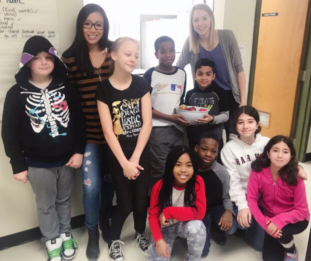 Amy Tung and a diverse group of youth smiling at school