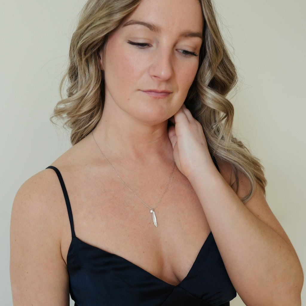 Sterling silver necklace with an intricate feather design and clear quartz pendant