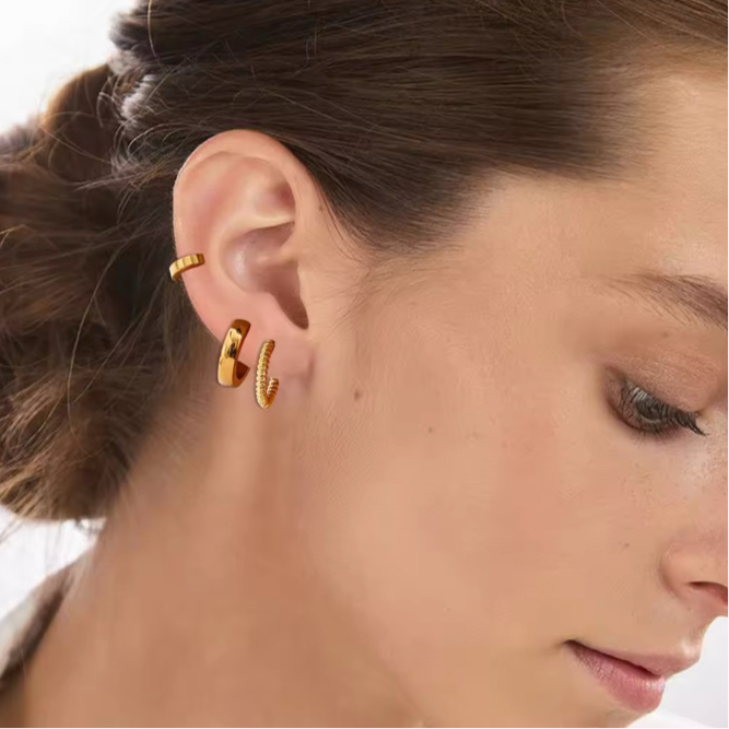 Women wearing three pairs of gold earrings 