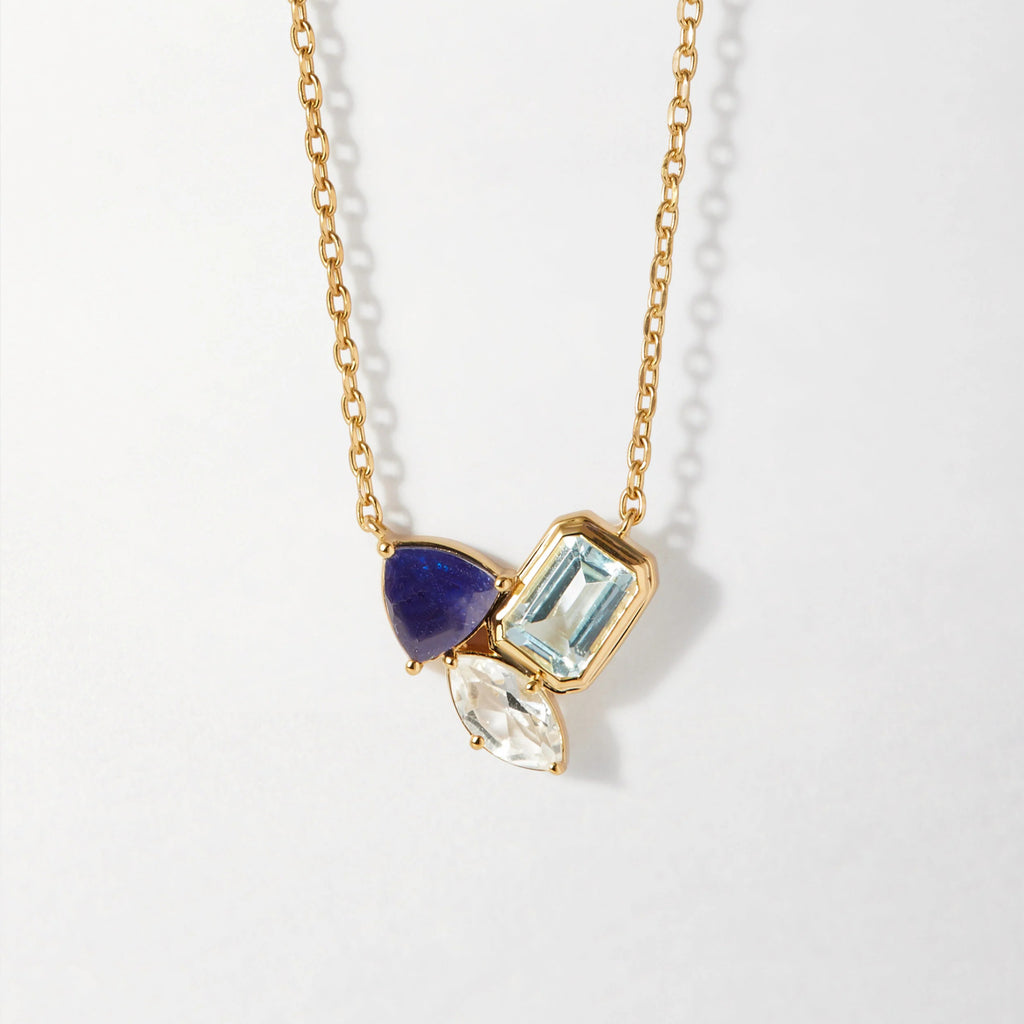Gold necklace with blue gemstone pendants on a light gray background