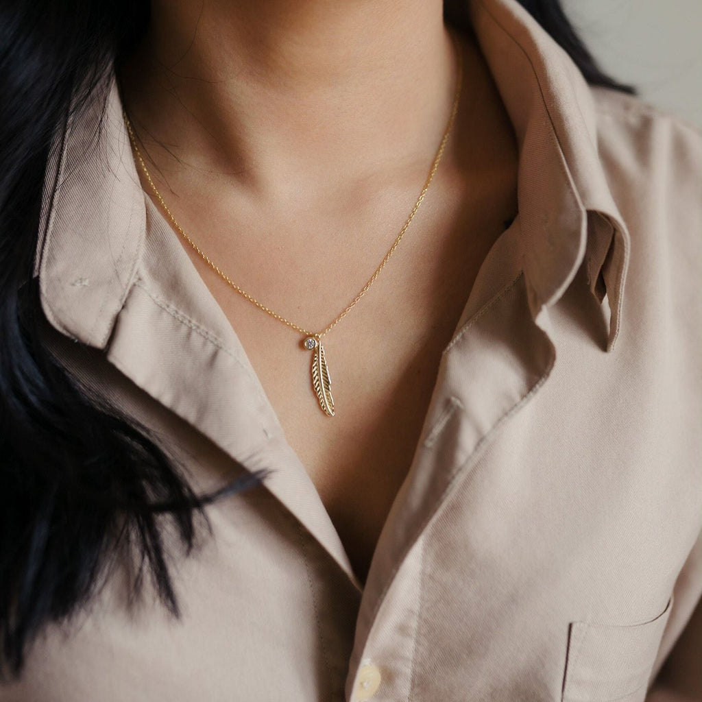 Sterling silver 14k gold necklace featuring an intricate feather design and a clear quartz pendant