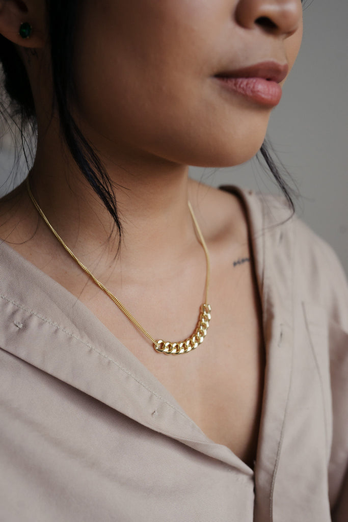 A striking 14K gold necklace with double strands. The center features ten larger link chains intertwined, adding a bold and stylish element. The golden shine and intricate design make it a luxurious accessory