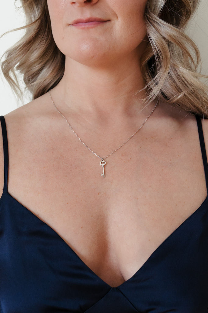 A stylish sterling silver necklace with a key-shaped pendant, designed by I Am Love Project. The pendant features intricate detailing and a sleek silver finish, creating an elegant and timeless accessory.