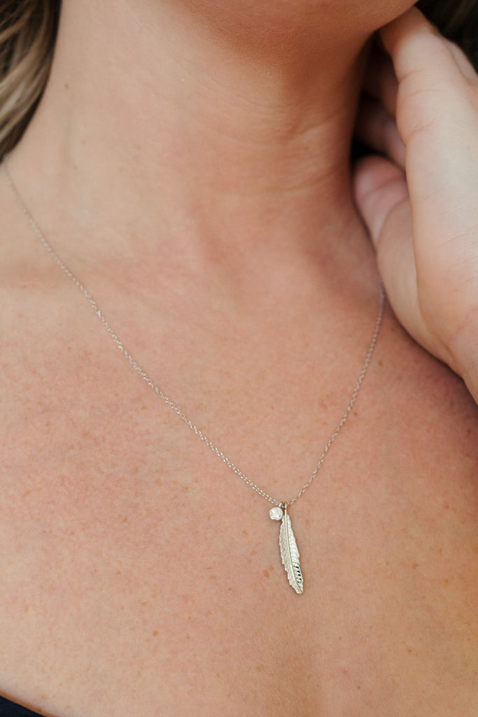 Sterling silver necklace featuring an intricate feather design and a clear quartz pendant