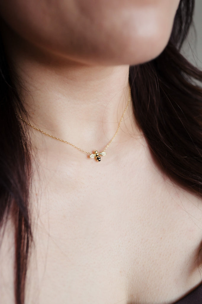 Dainty 14K gold necklace featuring a suspended bee pendant with black and cubic zirconia speckles on the wings