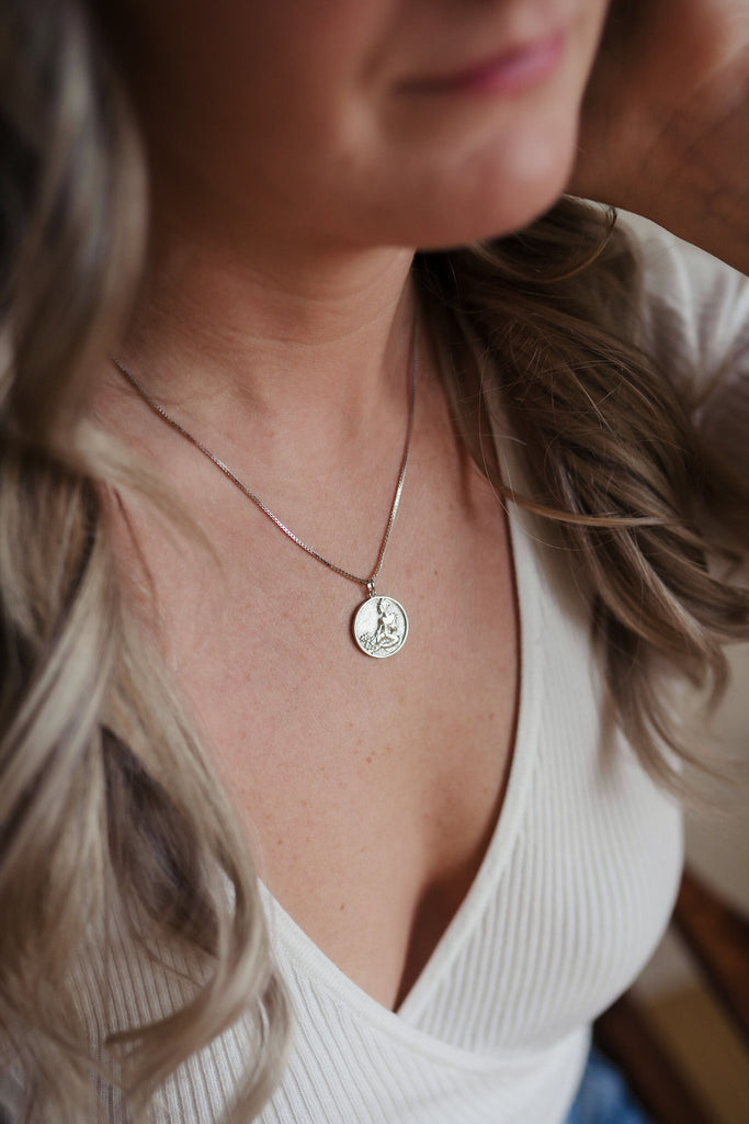 A beautiful sterling silver necklace with a delicate pendant in the shape of a coin, adorned with sparkling gemstones