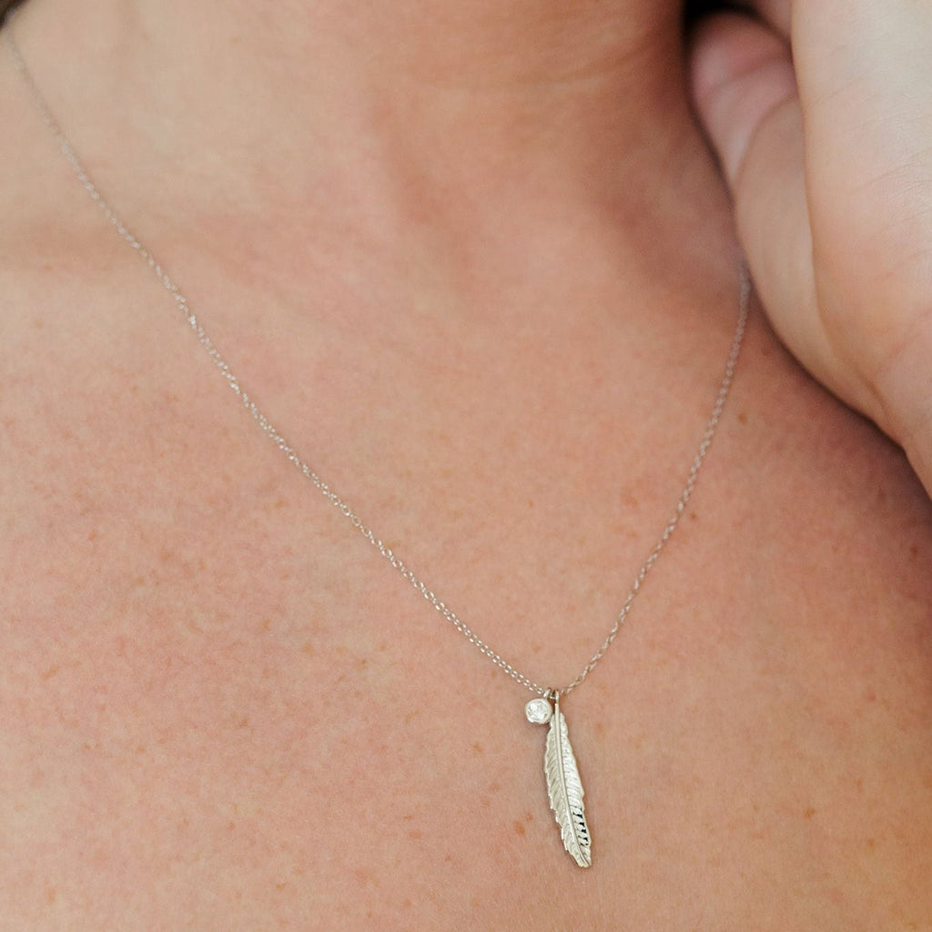 Sterling silver necklace featuring an intricate feather design and a clear quartz pendant