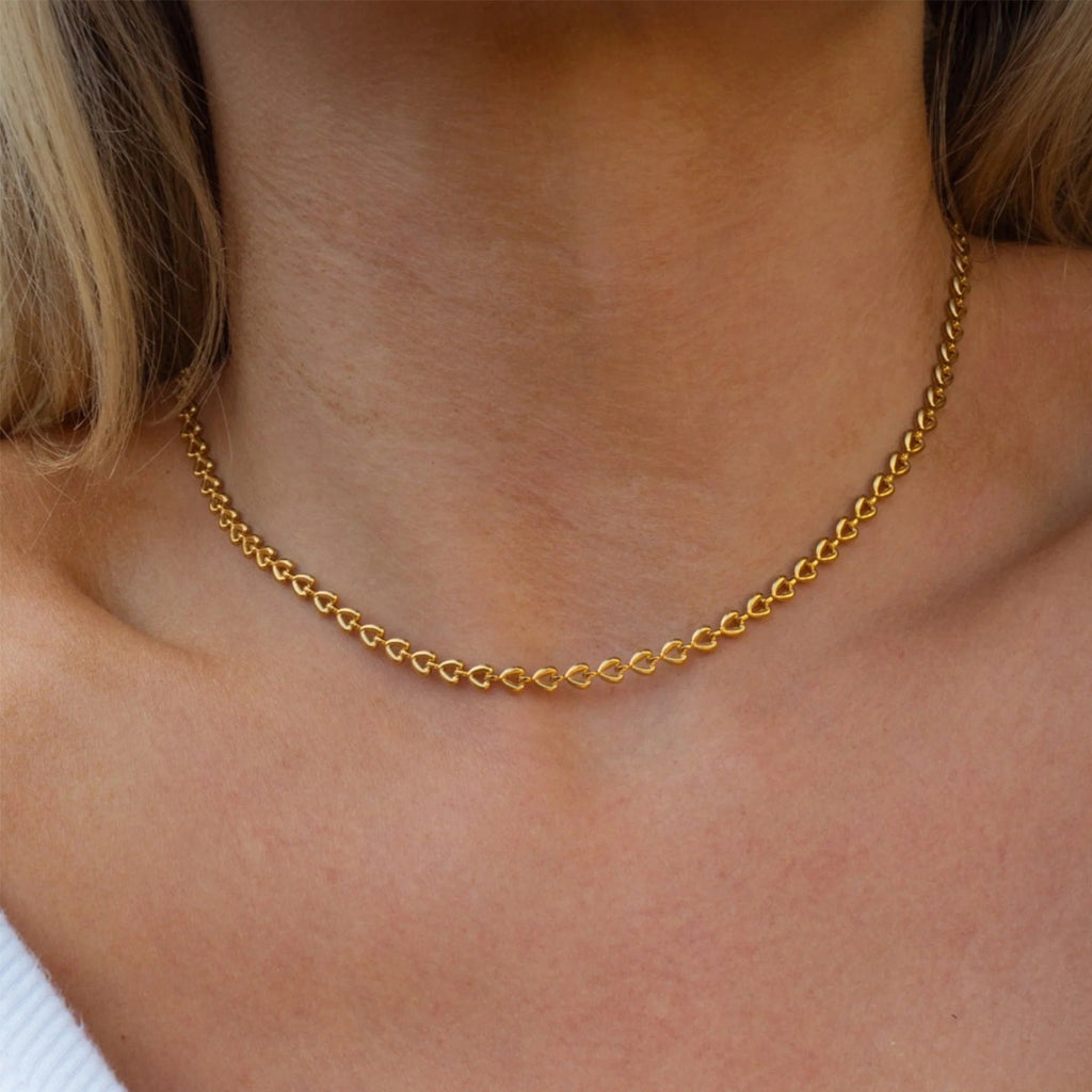 Gold heart chain necklace on a person's neck