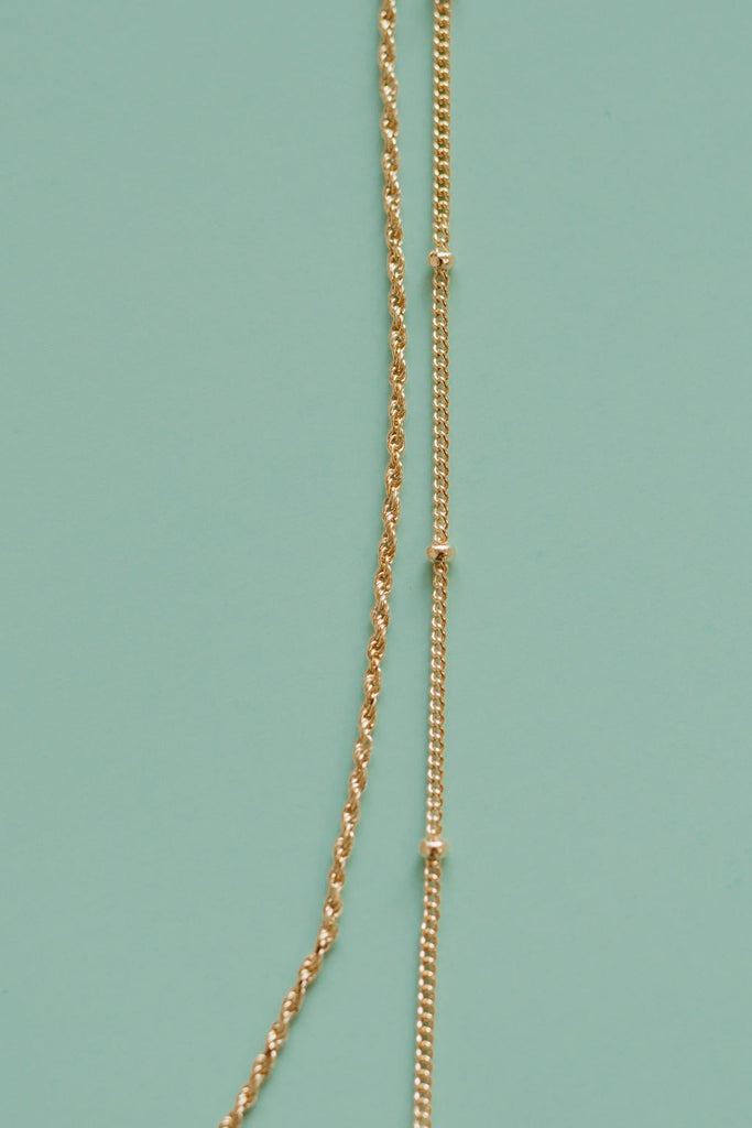 "I Am Love Project's 14K gold-plated layered affirmation necklace, showcasing a stylish combination of rope and satellite chains for a unique and meaningful accessory."