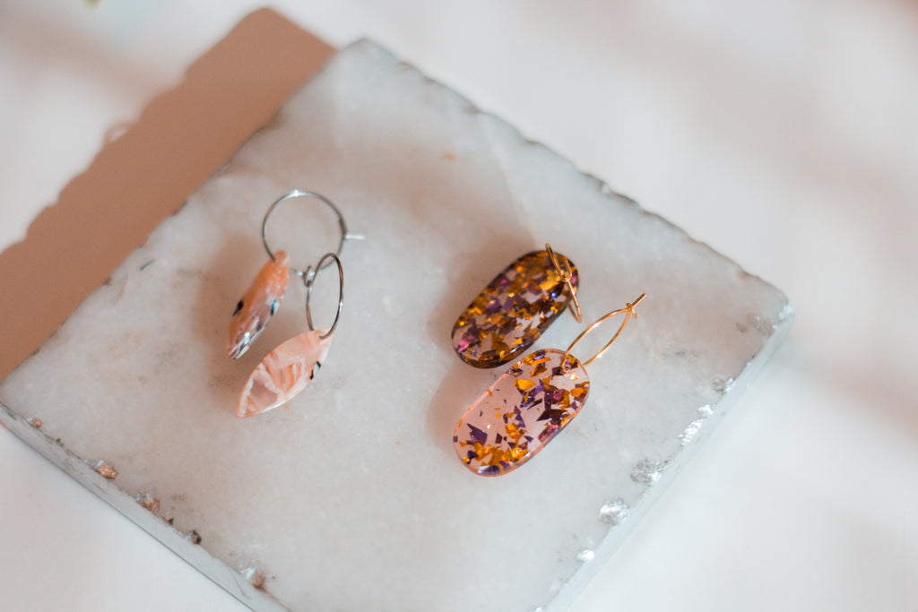 Artistic marbled pick-pointed acetate hoop earrings and oblong confetti hoop earrings.